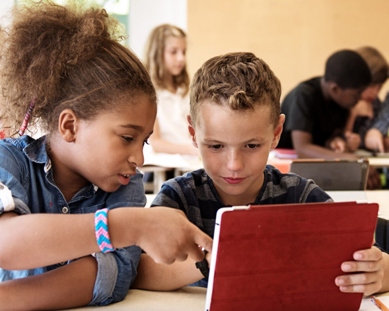 two kids looking at an ipad