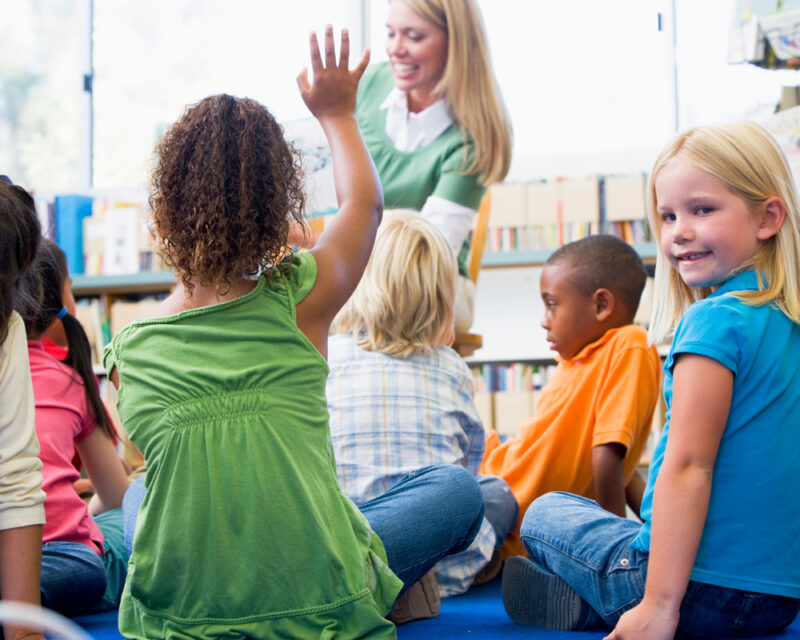 student raising hand in a classroom