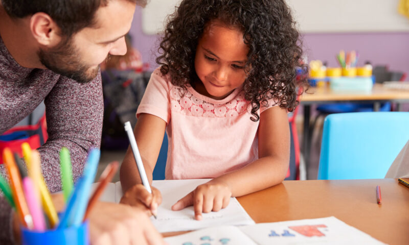 student writing with teacher