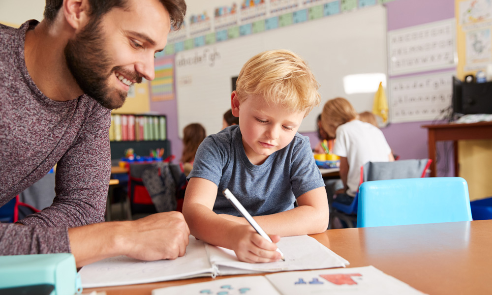 A teacher helps a student complete a math problem.